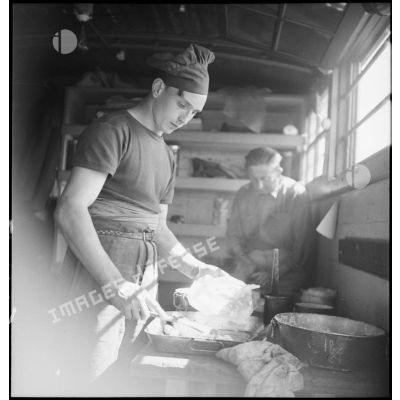 Un cuisinier de l'artillerie lourde sur voie ferrée (ALVF) fait la cuisine dans un wagon.
