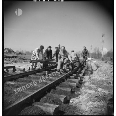 Des soldats de l'artillerie lourde sur voie ferrée (ALVF) mettent en place des rails de chemin de fer.