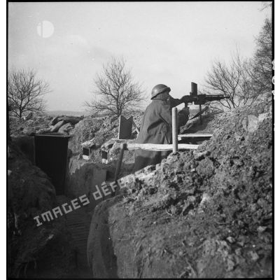 Un soldat de la 4e armée sert un FM 24/29 dans un poste de mitrailleur à l'intérieur d'une tranchée.