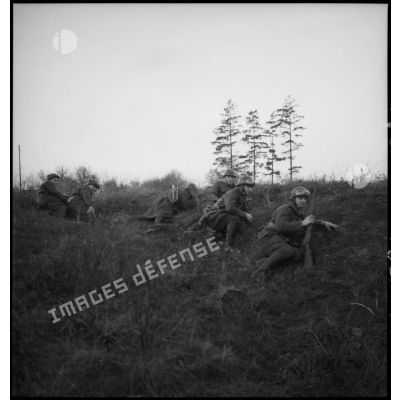 Photographie de groupe de soldats de la 4e armée couchés derrière un talus de terre.