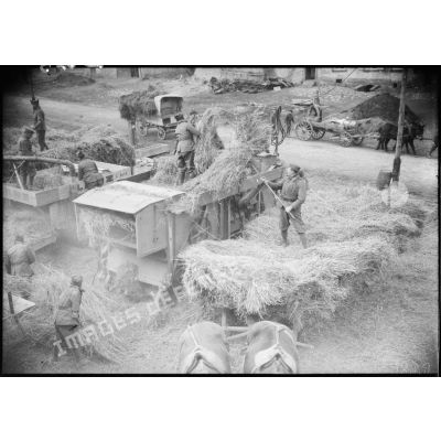 Des soldats réquisitionnés battent des céréales à l'aide d'une batteuse dans une zone évacuée de la 4e armée.