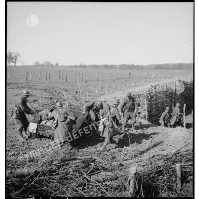 Près d'une tranchée des soldats de la 5e armée déchargent des caisses d'une remorque ou d'un engin non identifié.