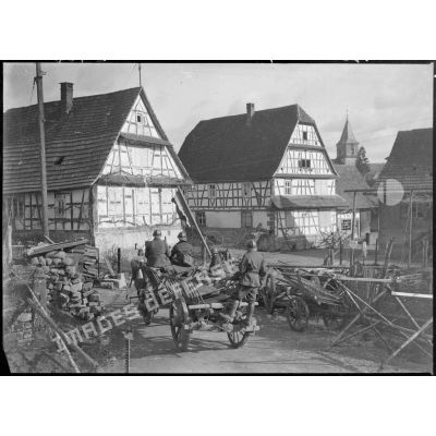 Une voiture hippomobile de la 5e armée rentre dans un village alsacien en contournant une barricade rudimentaire.