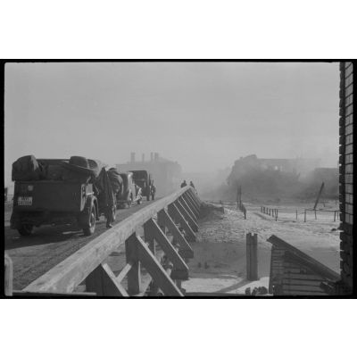 Des véhicules allemands patientent sur un pont avant de quitter Wjasma (Viazma), un insigne en forme d'écu pourrait correspondre au 9e corps d'armée (IX.Armeekorps).