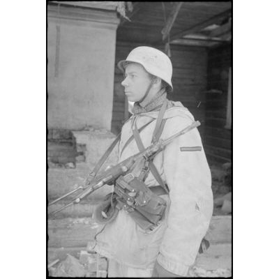 Durant la bataille de Witebsk, un fantassin allemand, armé d'un pistolet-mitrailleur MP-40, à l'abri d'une isba lors d'une contre-offensive.