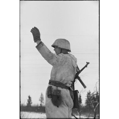 Un officier, armé d'un pistolet-mitrailleur MP-40, donne l'ordre d'assaut à des Jäger.