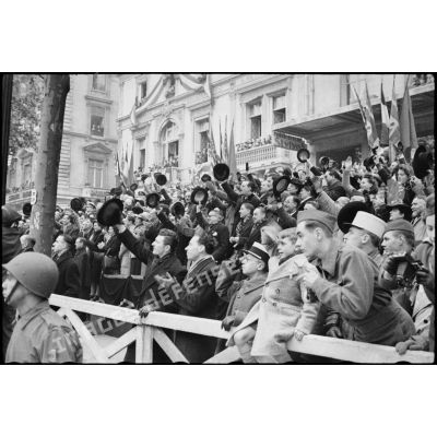 Foule immense acclamant le passage du général de Gaulle et de Winston Churchill, suivis du cortège des officiels, lors de leur descente des Champs-Elysées à l'occasion de la cérémonie du 11 Novembre 1944 à Paris.