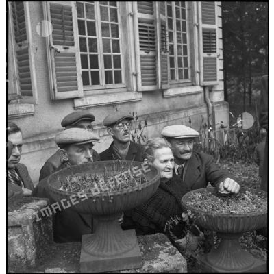 Quelques habitants observent au loin une prise d'armes au 2e RD (régiment de dragons) dans le parc d'un manoir le 5 novembre 1944.