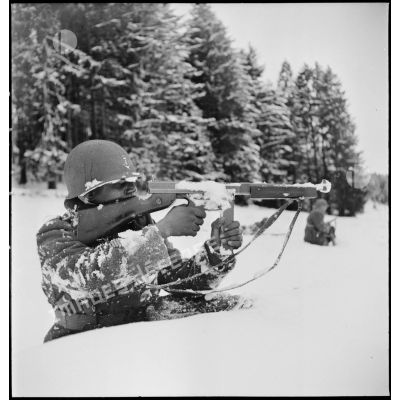 Tirailleur sénégalais de la 9e DIC progressant dans la forêt des Vosges enneigée, armé d'un pistolet-mitrailleur Thompson M1A1.