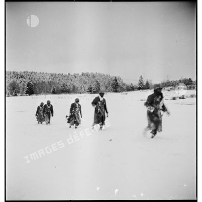Tirailleurs sénégalais de la 9e DIC (division d'infanterie coloniale) progressant dans la forêt des Vosges enneigée, armés de pistolets-mitrailleurs Thompson M1A1.