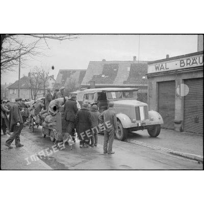 A Neudorf, avenue Jean Jaurès, les habitants du quartier du Port du Rhin (des ouvriers, polonais ou ukrainiens, requis par les autorités occupantes), se replient vers le centre de Strasbourg.<br>Semi-chenillé, tracteur d'artillerie ou de dépannage allemand, réquisitionné par la 2e DB.