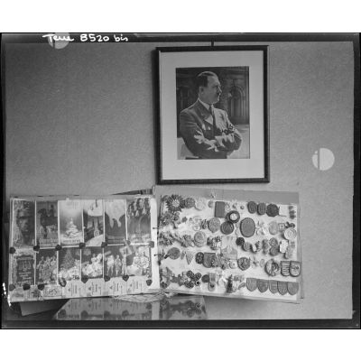 Album d'insignes nazis et portrait d'Adolf Hitler dans l'appartement d'un officier allemand investi par le 12e régiment de cuirassiers (12e cuirs) de la 2e division blindée (2e DB) près du pont de Kehl (Bas-Rhin).