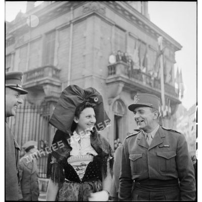 Le général de Lattre de Tassigny pose auprès d'une Alsacienne en costume traditionnel lors d'une cérémonie célébrant la libération de Belfort par les troupes de la 1re armée.