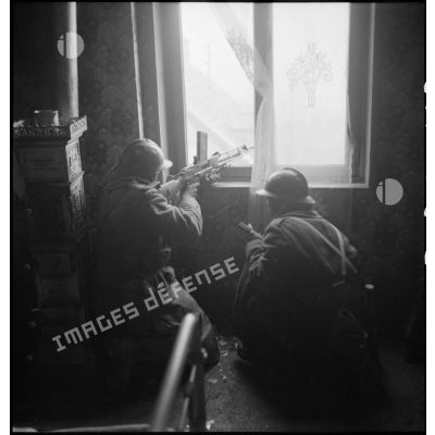 Guetteurs, équipés d'un fusil-mitrailleur FM M-24/29, en position de tir, dans une maison lors de la libération de Mulhouse.