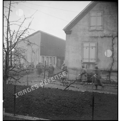 Patrouille de soldats de la 1re DB, équipés de fusils-mitrailleurs, entre les maisons de Mulhouse lors des combats livrés contre les troupes allemandes pour la reconquête de la ville.