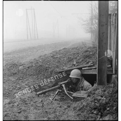 Soldat de la 1re DB (division blindée), guettant en position de tir, armé d'une mitrailleuse Browning M1919  7,62 mm et abrité dans un trou, dans les faubourgs de Mulhouse lors des combats livrés contre les troupes allemandes pour la reconquête de la ville.