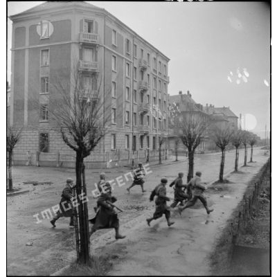 Soldats de la 1re DB (division blindée) progressant sous le feu dans une rue de Mulhouse, lors des combats livrés contre les troupes allemandes pour la reconquête de la ville.