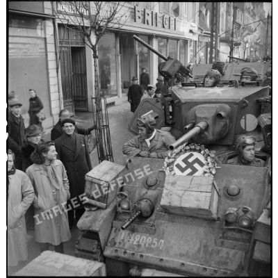 Défilé d'un char léger M3 Stuart de la 1re DB (division blindée) dans Mulhouse tout juste libérée de l'occupation allemande ; l'équipage salue la population à son passage.