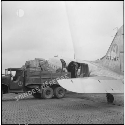 Terrain d'aviation de Bach Mai à Hanoï : chargement du ravitaillement (caisses, médicaments, essence) à bord d'un avion Douglas C-47B Skytrain (Dakota) pour les besoins du poste de Phong Saly.