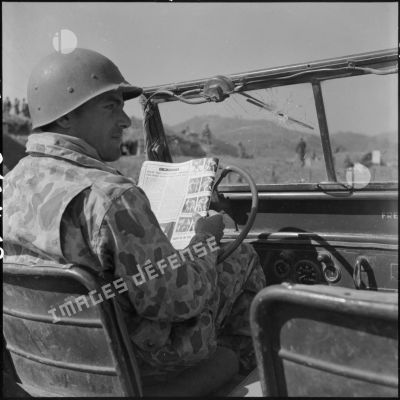 Un parachutiste lit le journal dans un véhicule à Na San.