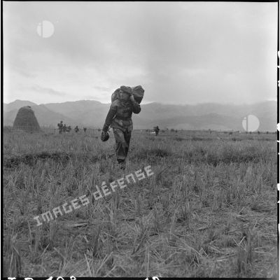 Portant son parachute replié, le général de brigade Gilles, commandant les troupes aéroportées en Indochine, s'avance vers le point de regroupement après son saut à Diên Bien Phu au cours de l'opération Castor.