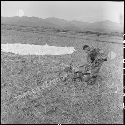 Un parachutiste se débarrasse de son équipement sur la dropping zone de Diên Biên Phu au cours de l'opération Castor.