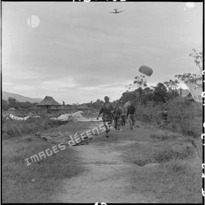 Parachutage de munitions au dessus d'un village où progressent des parachutistes, dans le cadre de l'opération Castor sur Diên Biên phu.