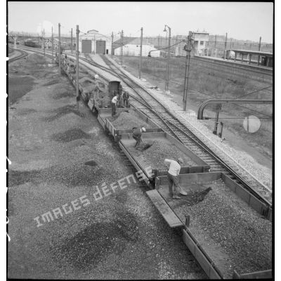 Des cheminots vident des wagons de ballast près de la gare ferroviaire de Massy.