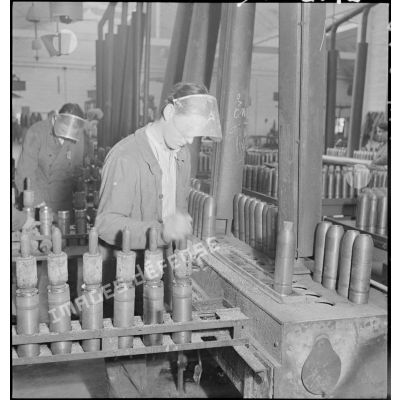 Plan général d'un atelier de l'usine de munitions où des ouvriers travaillent à la confection d'obus.