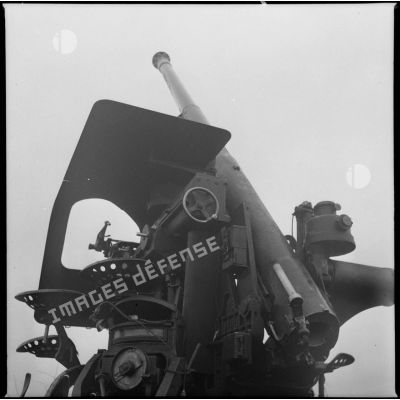 Un canon de 75 mm M17/34 est photographié de derrière en contre-plongée et en plan moyen.