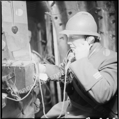 Portrait d'un capitaine du 404e RAAA qui utilise un téléphone de campagne à l'intérieur du poste de commandement.