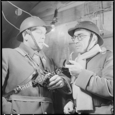 Portrait de groupe de deux officiers du 404e RAAA qui fument à l'intérieur du poste de commandement.