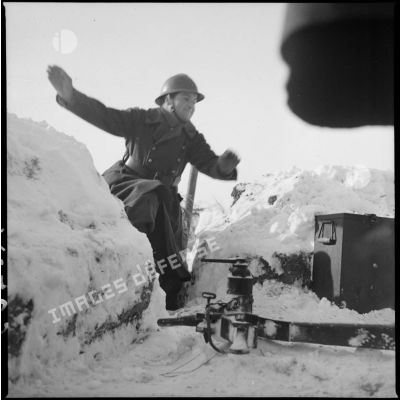 Dans la neige, un soldat d'une équipe de pièce du 404e RAAA se précipite vers le canon de DCA.