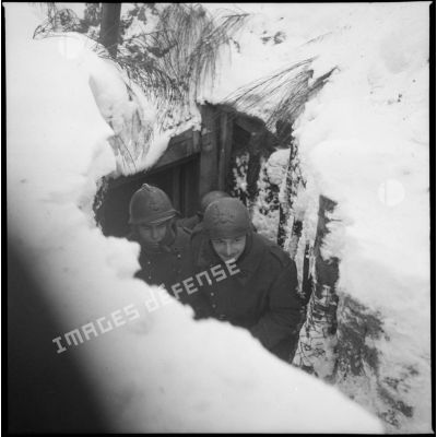Des personnels d'une équipe de pièce du 404e RAAA sont photographiés dans une tranchée enneigée.