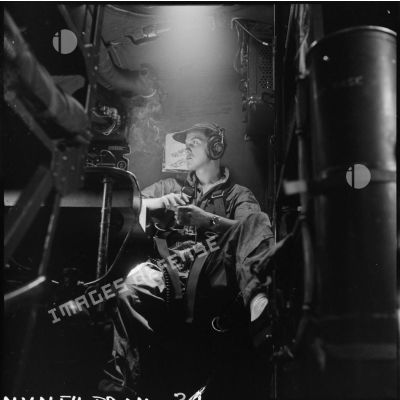 L'enseigne de vaisseau Tourel à bord d'un avion bombardier Privateer de la flottille 28F, fumant une cigarette.