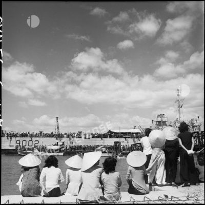 Sur le port, des Vietnamiennes observent l'embarquement de légionnaires quittant l'Indochine.