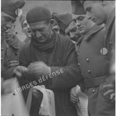 [Abbé vendant des journaux à des soldats, ferme Moncillon, Moselle. 26 octobre 1939.]