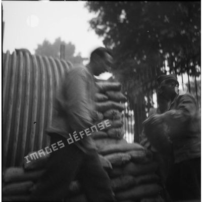 [Les soldats Victor Petit et Raymond Charmoille du SCA (service cinématographique de l'armée) préparant des sacs de sable.]
