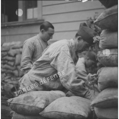 [Les soldats Victor Petit et Henri Goupy du SCA (service cinématographique de l'armée) préparant des sacs de sable.]