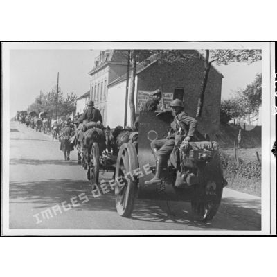 Un 155 mm court M1915/17 est photographié de trois quarts alors qu'il est attelé à une voiture hippomobile qui se déplace sur une route en convoi près du village de Nivelle.