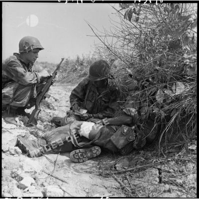 Un soldat blessé est soigné à l'abri des hautes herbes, lors d'une contre-attaque menée sur les positions Viêt-minh au sud de Diên Biên Phu.