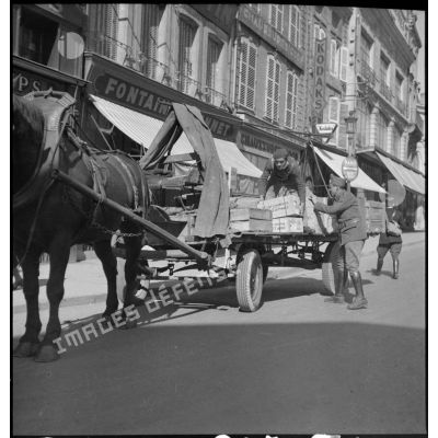 Plan général de soldats français qui chargent une charrette dans une rue.