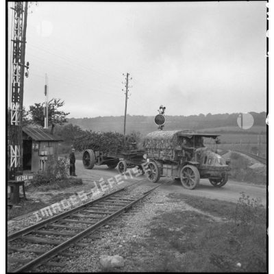 Un camion Latil TAR du 185e RA qui tracte un 145/155 mm M1916 traverse un passage à niveau.