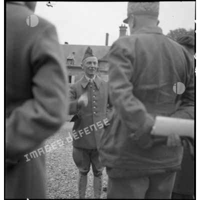 Le général d'armée Huntziger est photographié en pied alors qu'il discute avec des officiers qui l'entourent.