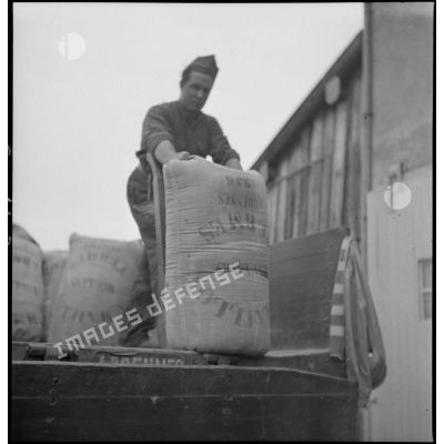 Des soldats de la 2e armée déchargent des sacs de farine d'un camion.