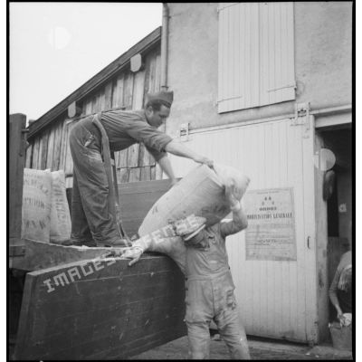 Des soldats de la 2e armée déchargent des sacs de farine d'un camion.