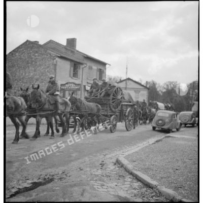 Un convoi hippomobile de la 2e armée traverse un village, il est photographié en plan général de trois quarts.