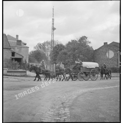 Un fourgon omnibus de la 2e armée traverse un village, il est photographié en plan général de profil.