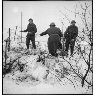 Trois soldats de la 2e armée sont photographiés alors qu'ils marchent dans un paysage enneigé.