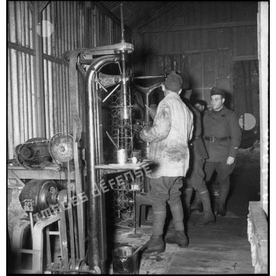 Des soldats de la 2e armée se tiennent dans un atelier près de machines-outils.